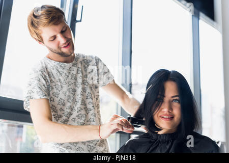 Parrucchiere con Pettine e forbici da taglio di capelli client femmina. Donna in parrucchiere salone di bellezza. Foto Stock