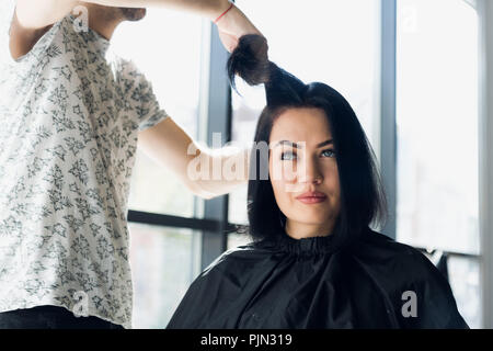 Irriconoscibile parrucchiere creazione di acconciatura per la bella bruna donna Foto Stock