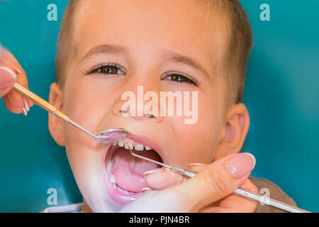 Dentista esaminando little boy i denti in clinica. Close up boy avente i suoi denti esaminati da un dentista. Un bambino presso la clinica dentale. Con i medici Foto Stock