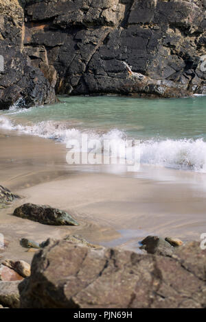 Onde di rotolamento delicatamente su una spiaggia di Pembrokeshire, Galles Foto Stock