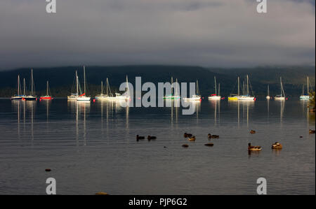 Sole di mattina su yachts, Spesse nuvole basse sulle colline, Milarrochy Bay, Loch Lomond Scozia, Regno Unito. Foto Stock