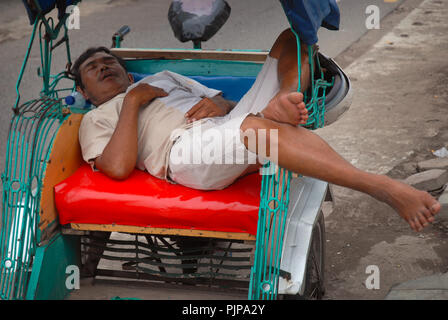 L'uomo addormentato nella sua cycle rickshaw, Yogyakarta, Java, Indonesia. Foto Stock