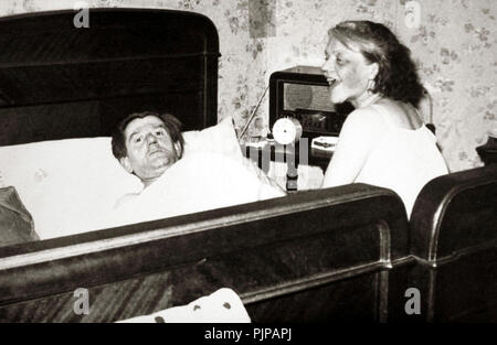 Matura in camera da letto, l'uomo è giacente in letto, donna è seduta accanto a esso, ridere, 1940s, Germania Foto Stock