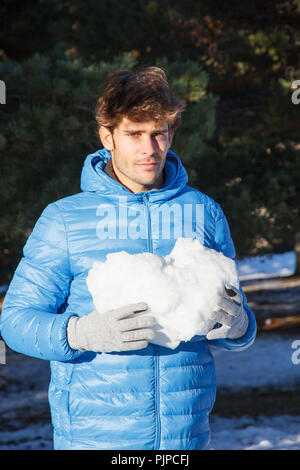 Giovane Azienda una grande palla di neve con le sue mani sulla montagna un inverno nevoso giorno. Foto Stock