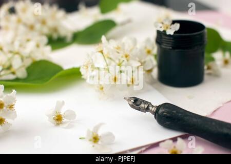 Buste, carta, fiori di colore bianco, nero inchiostro e penna stilografica. Stile scrivania femminile area di lavoro con fiori di colore bianco, calligrafia pennino, inchiostro, Busta e di Pentecoste Foto Stock