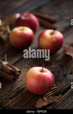 In autunno le mele rosse con bastoncini di cannella. Autunno stagionali di cottura Ingredienti di pasticceria - mele, noci e spezie in legno rustico sfondo. Foto Stock