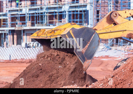 La costruzione dei terrapieni macchina livellatrice ribaltamento della benna terra closeup formato cantiere. Foto Stock