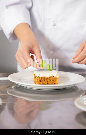 Professione di cuoco femminile al lavoro come donna in uniforme e cappello  bianco taglia il salmone su una tavola di legno in una cucina professionale  Foto stock - Alamy