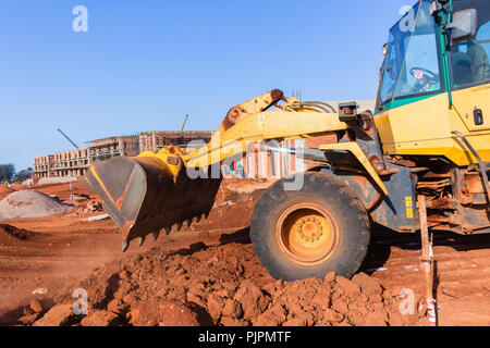 La costruzione dei terrapieni macchina livellatrice ribaltamento della benna terra closeup formato cantiere. Foto Stock