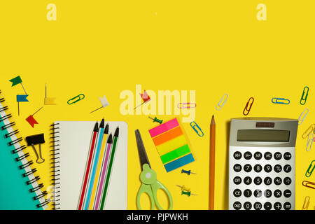 Più la scuola e forniture per ufficio e gadget giacenti su uno sfondo giallo. copyspace libero Foto Stock