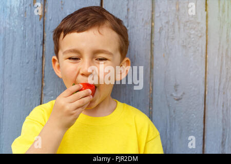 Bambino kid little boy mangiare fragole estate fragole copyspace copia spazio all'aperto all'aperto al di fuori la molla Foto Stock