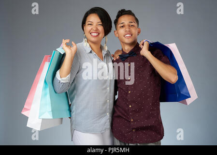 Sorridenti coppia giovane con coloratissime shopping bags isolato su grigio di sfondo per studio Foto Stock