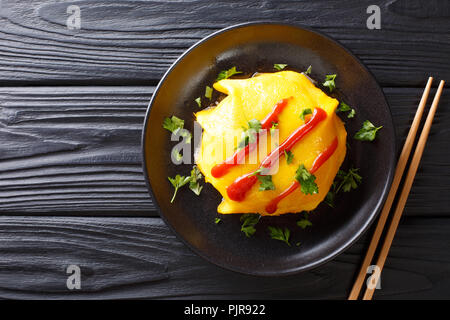 Omurice deliziose omelette ripiene con riso, pollo e verdure servita su un piatto sul tavolo. parte superiore orizzontale vista da sopra Foto Stock