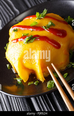 Giapponese omurice omelette ripiene con riso, pollo e verdure close-up su una piastra su un piano verticale. Foto Stock