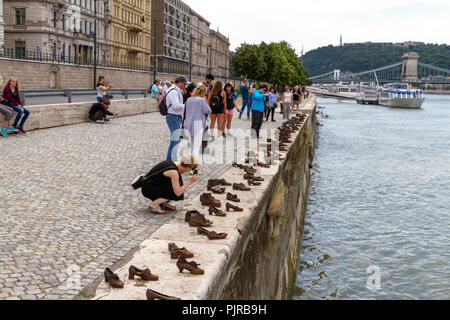 I turisti che visitano le scarpe sulla sponda del Danubio Memorial, concepito da può Togay scolpito da Gyula Pauer, il fiume Danubio, Budapest, Ungheria. Foto Stock