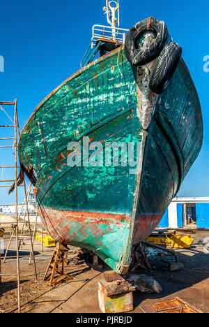 Le riparazioni sulla prua di una barca da pesca nel bacino di carenaggio del porto di Essaouira in Marocco Foto Stock