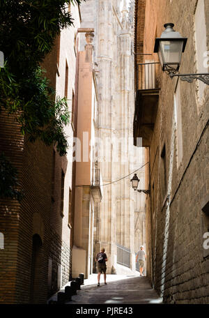Un uomo a piedi lungo una strada con edifici molto alti che incombe su di lui, Barcellona, Spagna Foto Stock