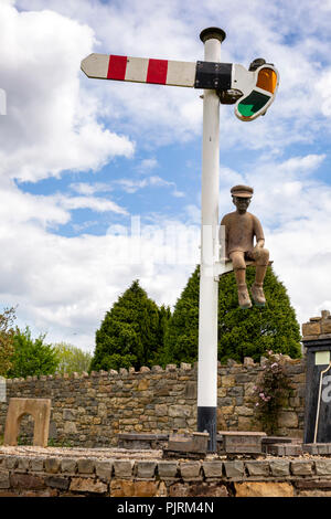 Irlanda, Co Leitrim, Dromod, Village Center, ferroviaria scultura con giovane ragazzo seduto sul segnale Foto Stock