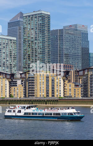 Battello da crociera sul Fiume Tamigi con Canary Wharf grattacieli in background, Londra England Regno Unito Regno Unito Foto Stock