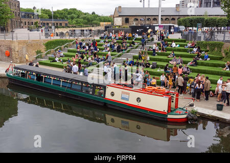 Per coloro che godono di un clima caldo e sui gradini in piazza granaio a King's Cross, Londra England Regno Unito Regno Unito Foto Stock