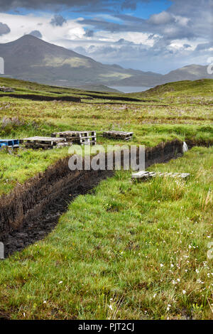 Trench tagliato in profondità la torba e la conservazione delle zone umide mori presso Drinan sull isola di Skye in Scozia con il Loch Slap e Beinn Na Caillich picco di montagna Foto Stock
