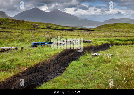 Trincee tagliato in profondità la torba e la conservazione delle zone umide mori presso Drinan sull isola di Skye in Scozia con il Loch Slap e Beinn Dearg Mhor e Beinn Na Caillich picchi Foto Stock