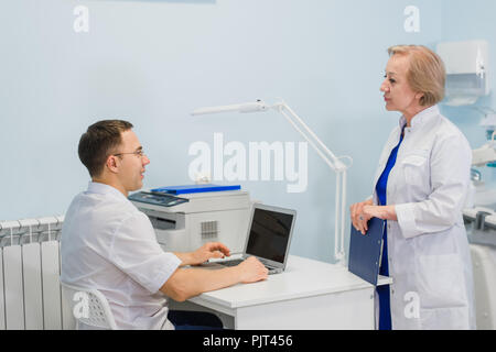 Senior medico suggeriscono l uomo medico con computer portatile in ufficio Foto Stock