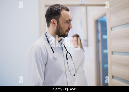 Triste pensieroso medico soggiornando nel corridoio di ospedale Foto Stock