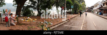 Due turisti tenendo fotografia di rifiuti sinistra dietro in Khem Khong strada dopo il Lao festa di Capodanno in Luang Prabang Foto Stock