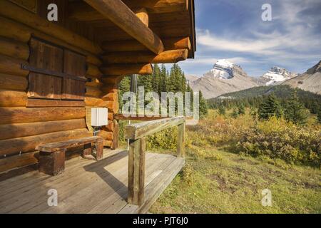 Park Ranger cabina in legno esterno e in lontananza Snowy Rocky Mountain Peaks in Red Deer River Valley, Banff National Park, Canadian Rocky Mountains Foto Stock
