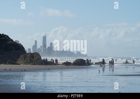 Spiaggia con rocce in Costa d'Oro in Australia, con lo skyline di Surfers Paradise in background Foto Stock