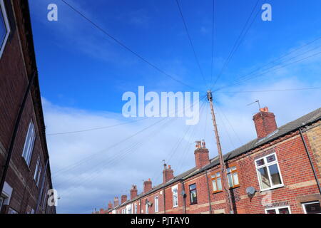 I cavi telefonici riempiono il cielo tra una fila di case a schiera a Castleford Foto Stock