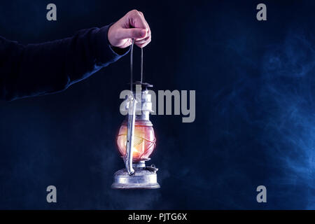 Man mano che trattiene il gas lanterna sul buio e notte fumato sfondo velato. Il gas o l'olio lampada accesa. L' orrore e la nozione di Halloween. Close up Foto Stock