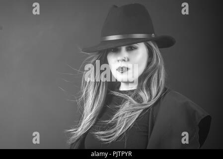 Studio ritratto di una donna rosso in un cappotto e cappello nero guardando la fotocamera Foto Stock