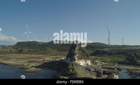 Formazione rocciosa naturale di pietra calcare sulla costa con mulini a vento per la produzione di energia elettrica. Vista aerea di attrazione turistica Kapurpurawan Rock Formazione in Ilocos Norte Filippine,Luzon. Foto Stock