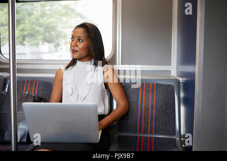 Imprenditrice utilizzando laptop sul treno Foto Stock