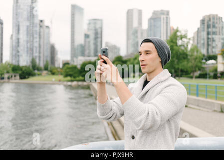 Giovane uomo prendendo foto sul Seawall, Yaletown, Vancouver, Canada Foto Stock