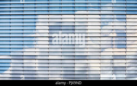 Il cielo blu con nuvole riflettono in un moderno edificio con facciata in vetro, moderno sfondo architettonico. Foto Stock