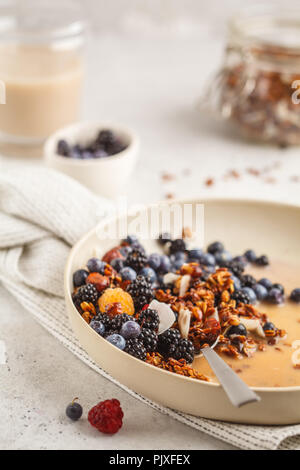 Fatti in casa con muesli e noci di cocco con frutti di bosco e latte in una piastra bianca. Pulire il concetto di mangiare. Foto Stock