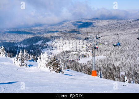 Ski resort, sulle piste da sci le persone sullo ski lift, montagne, le case e gli edifici panorama Foto Stock