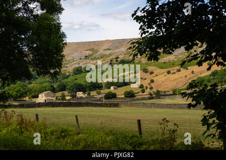 Un piccolo edificio in pietra in un campo inglese, incorniciato da alberi Foto Stock