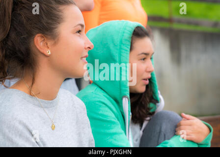 Due attraenti femmine giovani studenti con capelli castani guardare una partita intensamente Foto Stock