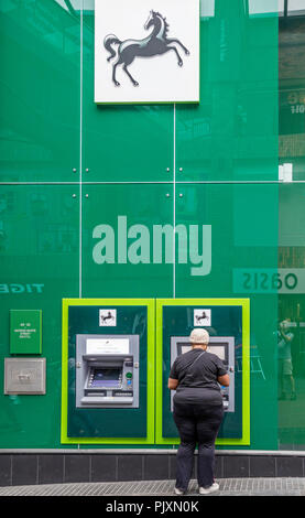 Signora usando un Lloyds Bank bancomat, Bristol, Inghilterra, Regno Unito Foto Stock