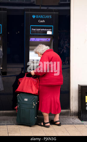 Signora anziana utilizzando un Barclays Bank bancomat, Bristol, Inghilterra, Regno Unito Foto Stock