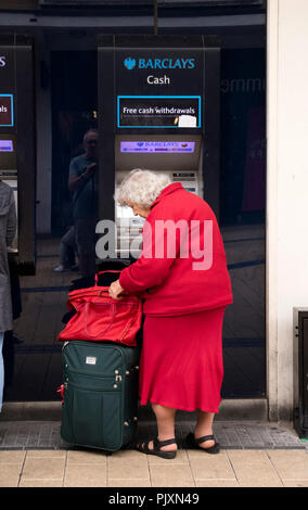 Signora anziana utilizzando un Barclays Bank bancomat, Bristol, Inghilterra, Regno Unito Foto Stock