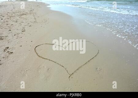 Cuore nella sabbia dipinta con wave sul lato Foto Stock