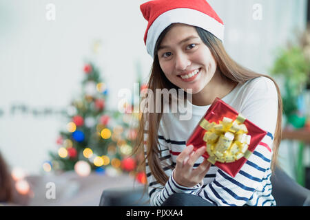 Asia donna sorriso holding gold xmas confezione regalo a festa con decoro bandiera a sfondo,presente dando Christmas party presente,vacanze inverno Foto Stock