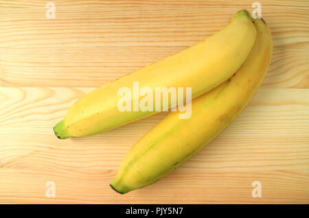 Vista dall'alto di due colori brillanti giallo mature Banane fresche isolate su un tavolo di legno Foto Stock