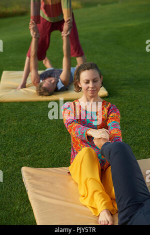 Toccando la gamba di massaggio, la pratica dello yoga. Foto Stock