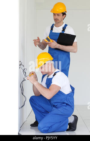 Due costruttori che lavorano con l'elettricità in ambienti chiusi in casa nuova Foto Stock